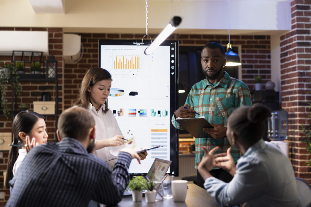 Close up of a young and diverse business team working together while preparing for a presentation, reflecting small business coaching certification, small business coaching tools, and a collaborative small business coaching framework.