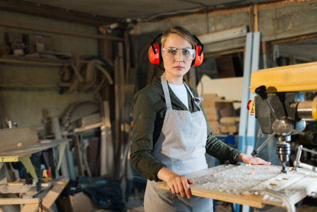 Skilled worker using a drill press in a small business, representing job creation and local employment.